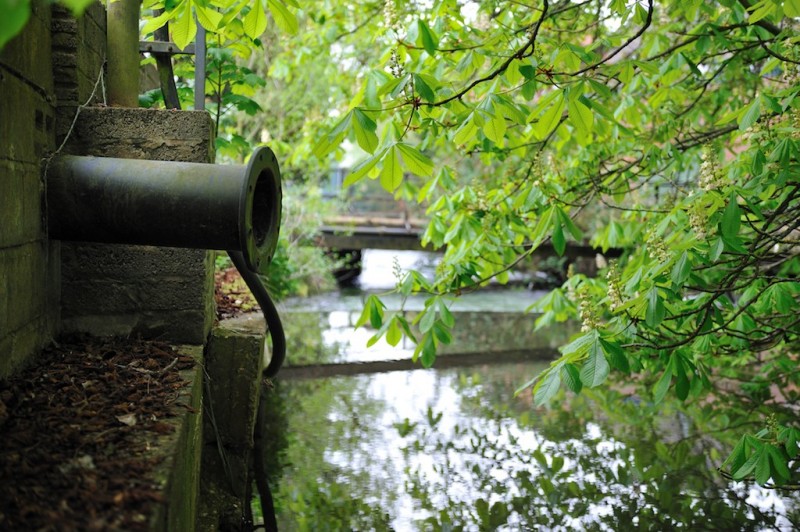 A rusting pipe waits poised above a stream at the edge of Laverstoke Mill