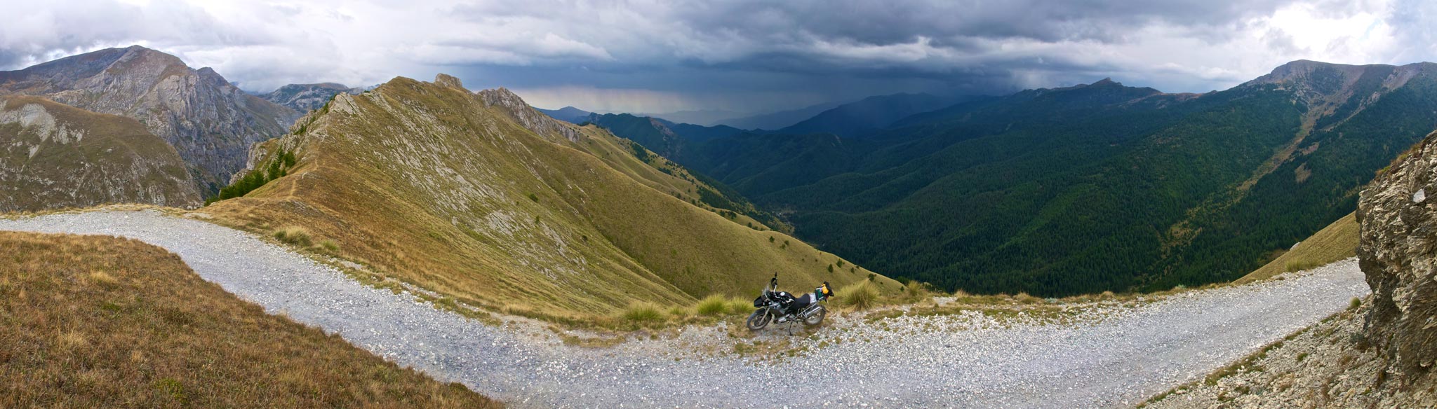 Panorama of bike on a mountain track, thunderstorm in distance