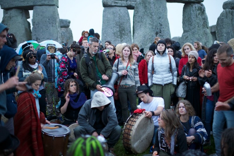 An eclectic band plays a range of percussion instruments in front of the stones