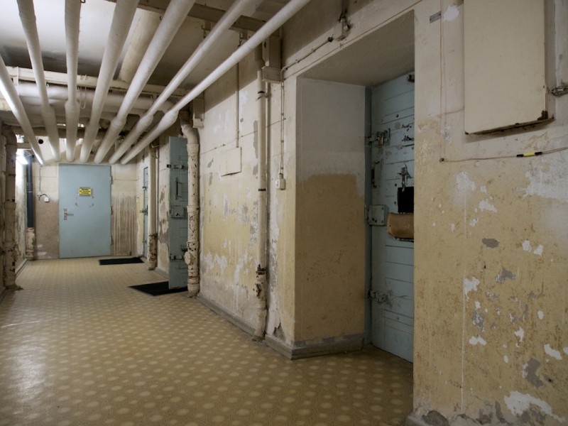 Cell doors line a dimly lit corridor