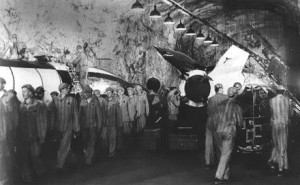 Small black and white photo showing concentration camp prisoners working on a rocket in a tunnel