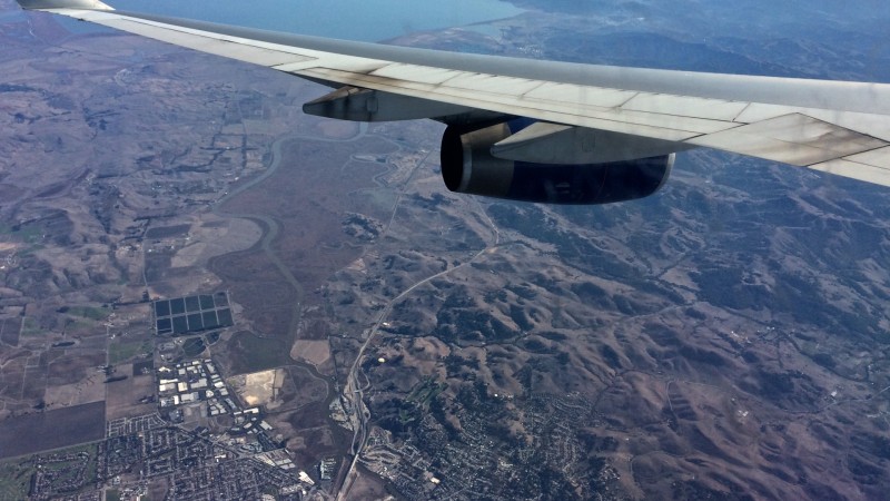 View onto distant landscape beneath dirty aircraft wing