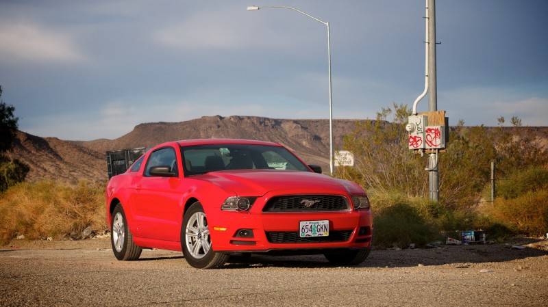A red Ford Mustang parked in front of a gratified streetlight